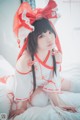 A woman in a red and white outfit sitting on a bed.