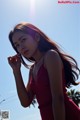 A woman in a red dress standing in front of a blue sky.