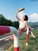 A woman sitting on top of a red and white barrier.