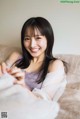 A woman sitting on a couch smiling at the camera.