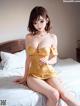 A woman in a yellow dress sitting on a bed.