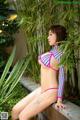 A woman in a colorful bikini sitting on a ledge.