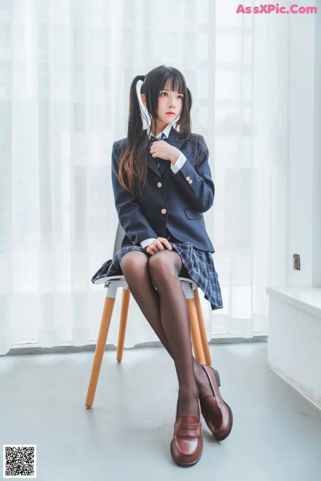 A woman in a school uniform sitting on a chair.
