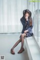 A woman in a school uniform sitting on a window sill.