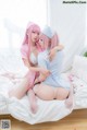 A couple of women sitting on top of a bed.
