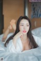 A woman laying on top of a bed in a white robe.