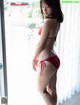 A woman in a red bikini standing by a window.