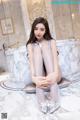 a woman sitting on top of a marble floor next to a bathtub
