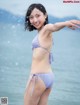 A woman in a purple bikini standing in the water.