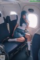 A woman sitting on an airplane with her legs crossed.